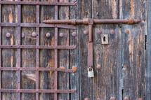 old wooden door with wrought iron bars. Old latch wrought iron.
