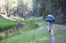 hiker with camping gear on his back walking on a trail 