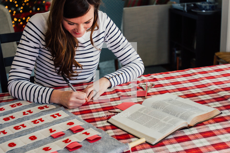 A woman writing Bible verses down to put in an Advent calendar 