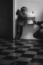 toddler boy drinking at a water fountain 