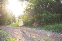 woman standing on a dirt road in a sundress 