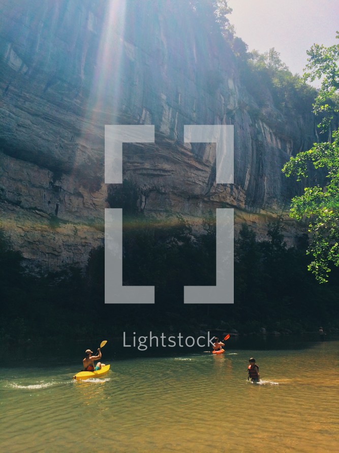 rays of sunlight on a river and people kayaking 