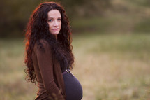 Pregnant woman standing in a field.
