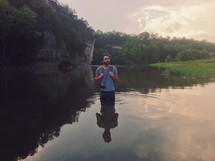 man standing in a a pond in waist deep water