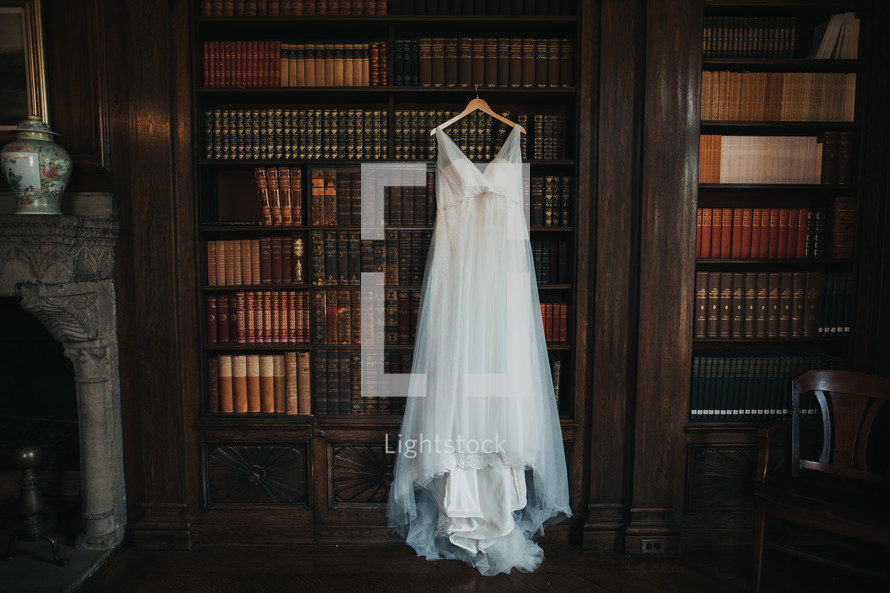 wedding dress hanging in a library 