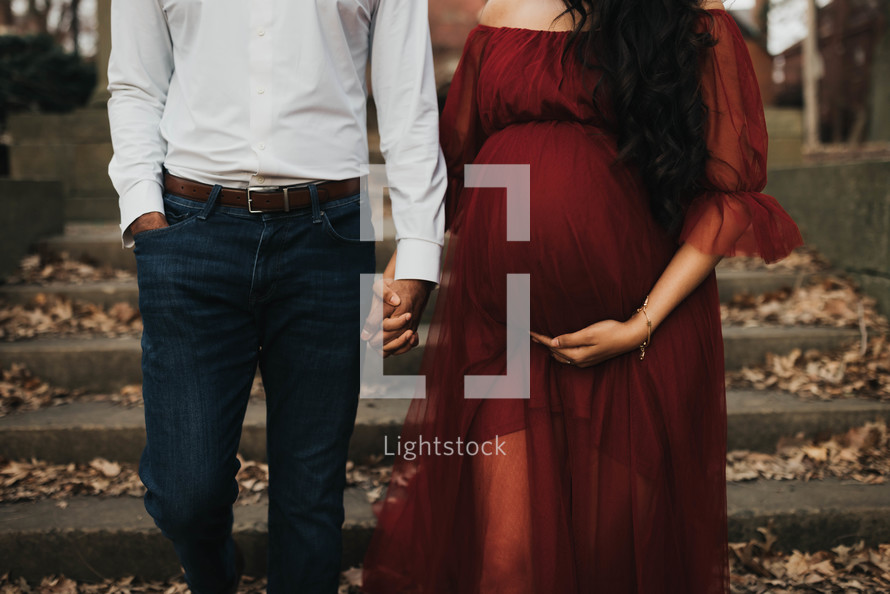 a pregnant woman and her husband hold hands