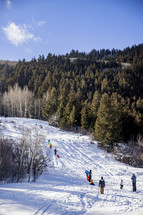 people sledding in snow on a hill 