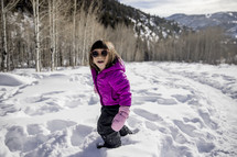 a child in a snowsuit standing in snow 
