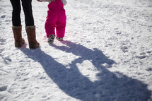a mother and her toddler daughter playing in snow 