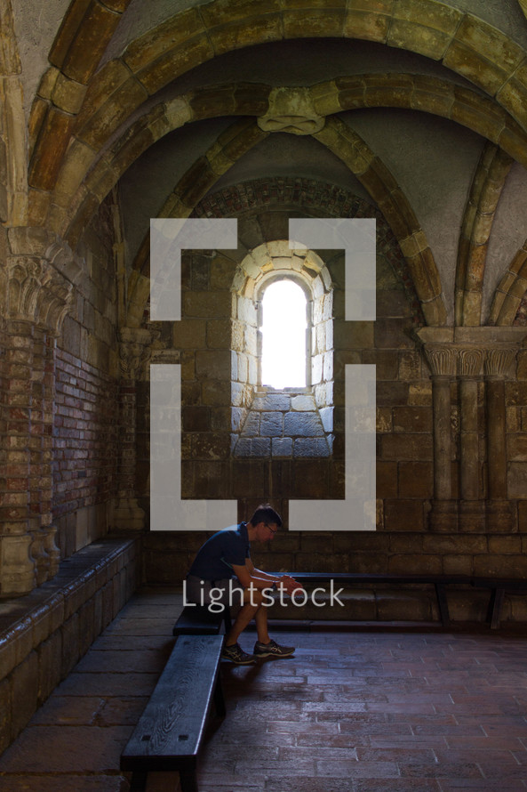 man praying under an arched stone ceiling