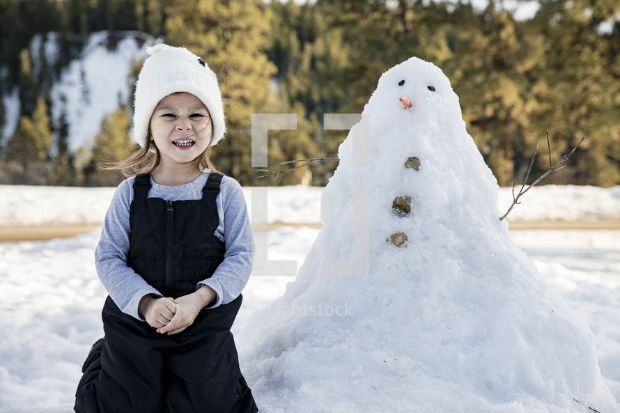 child and snowman outdoors in winter 