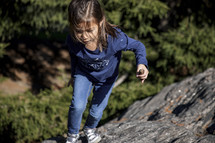 Little girl playing on a rock