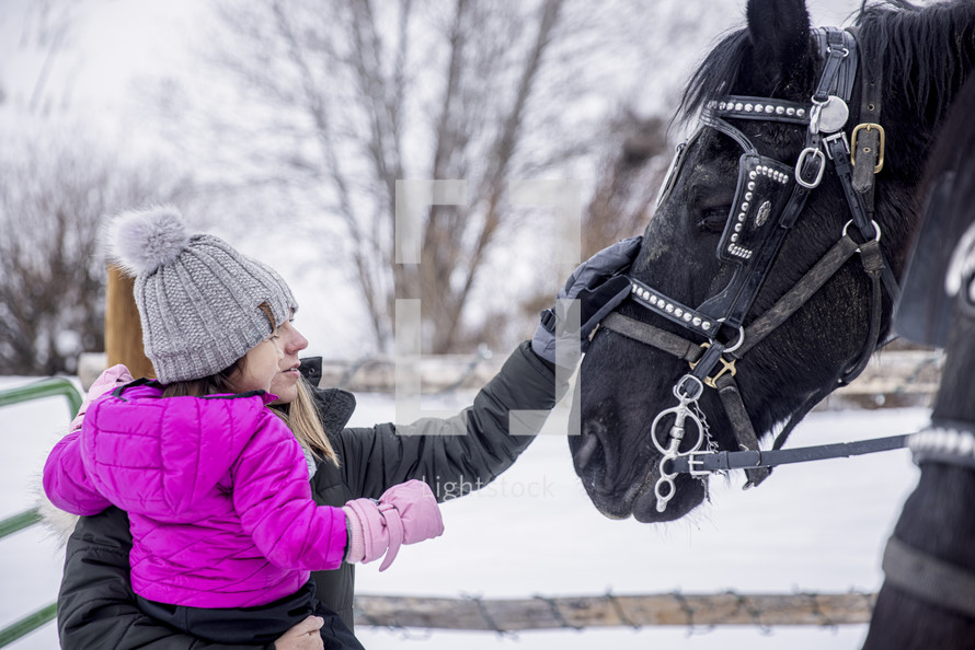 mother and child petting a horse in snow 