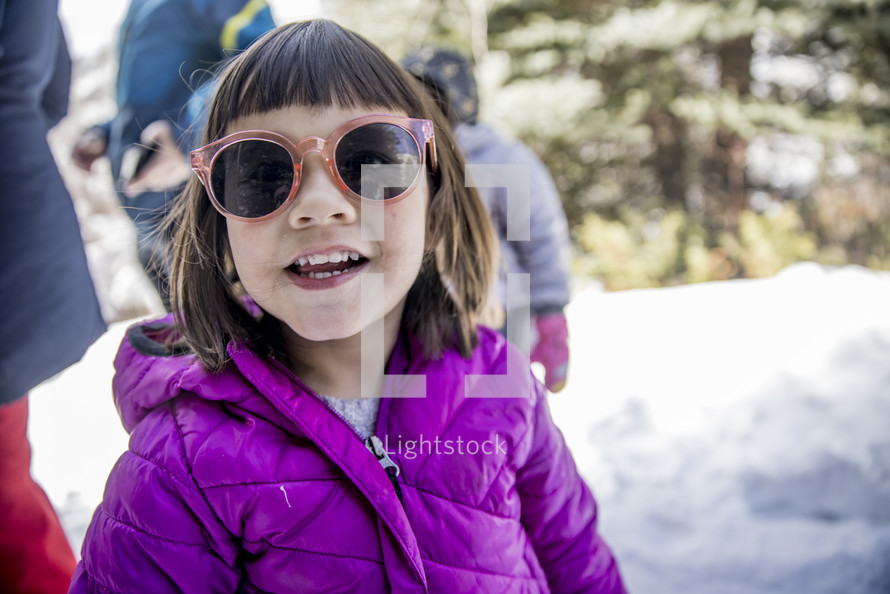 girl in sunglasses standing in snow 
