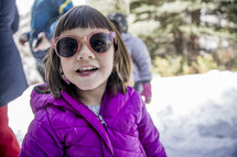 girl in sunglasses standing in snow 