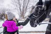 mother and child petting a horse in snow 