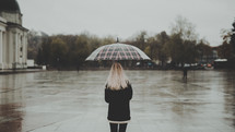 a woman standing under an umbrella on a rainy day 