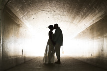 silhouette of a bride and groom kissing in a tunnel 