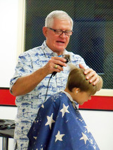 a barber giving a free haircut to a young boy at a church sponsored ministry to children.