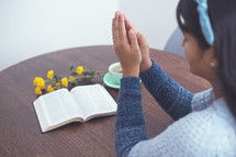praying hands and Bible on a table 