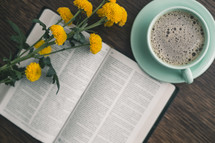 yellow flowers on the pages of a Bible and coffee cup 