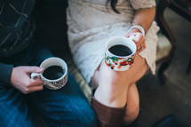 couple holding mugs of coffee over their laps 