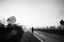 a silhouette of a woman standing on the side of a road dancing 
