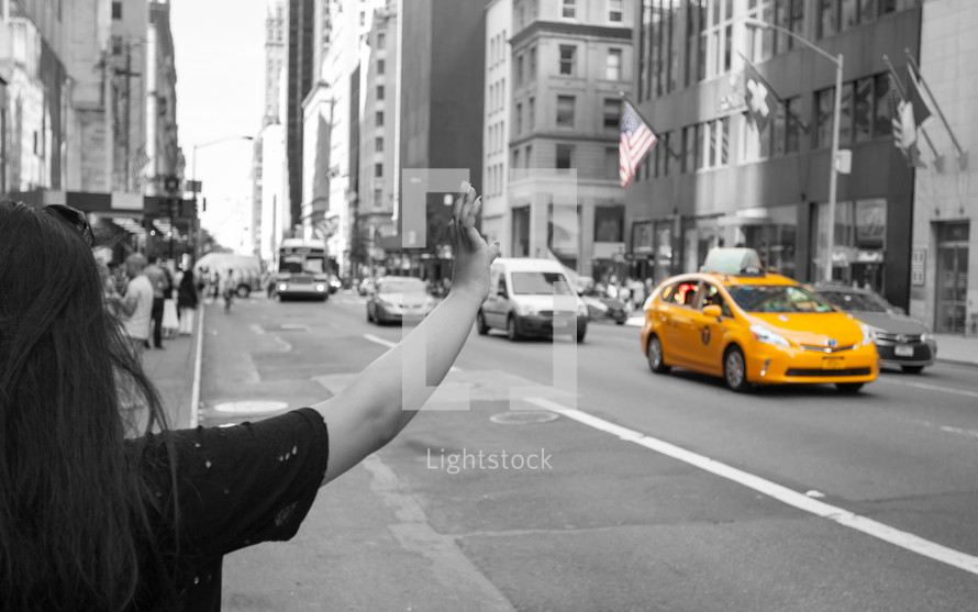 Tourist calls a yellow cab in Manhattan with typical gesture with arm up.
