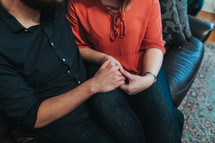 a couple sitting on a couch holing hands