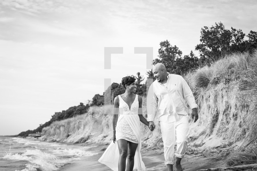 couple holding hands walking on a beach 