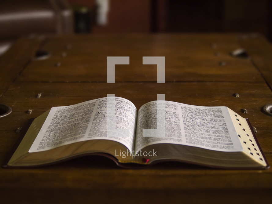 Bible laying open on a wooden table.