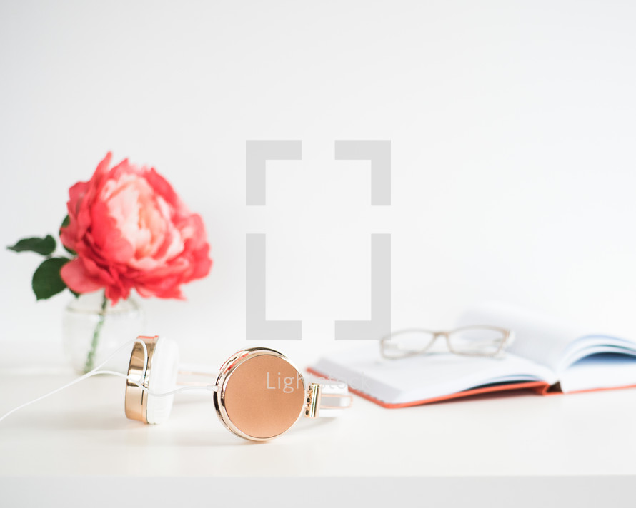 headphones, flower, vase, journal, and reading glasses 