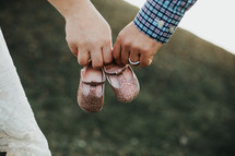 expecting couple holding baby girl shoes 