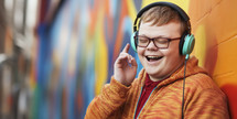 Happy young man with Down syndrome enjoying music on his headphones, feeling the rhythm against a colorful mural.