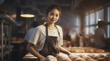Portrait of a young and beautiful female asian baker kneading dough in a bakery.