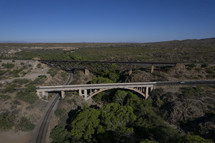 Aerial of a train trestle and highway bridge over a wooded canyon