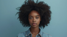 Serene young woman in denim jacket with natural hair.