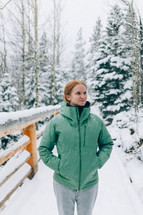 female hiker walks in the mountain woods as snow falls around her 