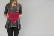 a woman holding a wooden heart 