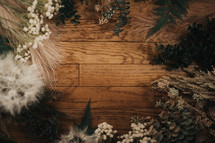 frame of plants, grasses, and flowers on a wood background 