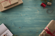 border of wrapped gifts on a wood floor with a Christmas gift list.