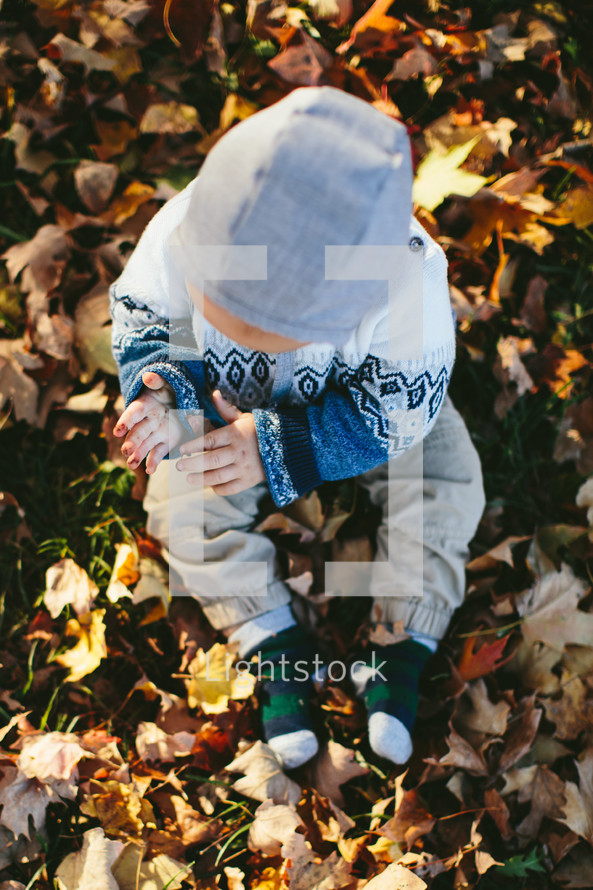 a toddler playing in fall leaves 