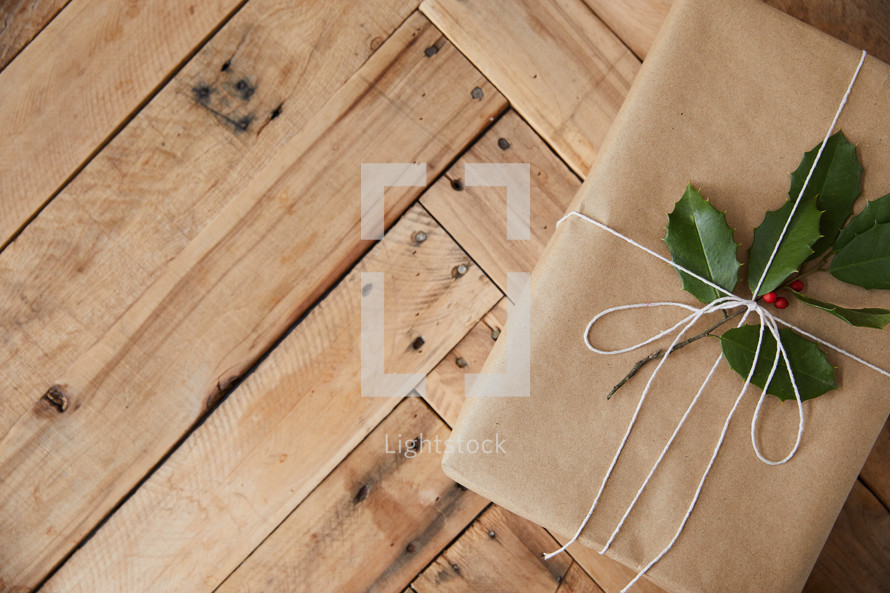 holly on a brown paper gift on a  wood background 