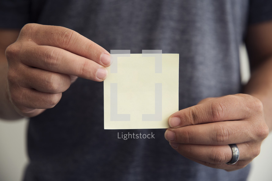 man holding a blank post-it note 