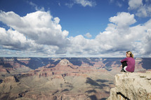 woman sitting at the edge of a canyon cliff 