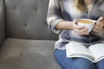 woman sitting on a couch reading a Bible and a cup of coffee 