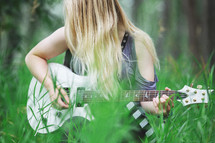 a young woman playing a guitar outdoors 