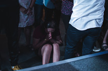 woman sitting on the floor and praying during a worship service 