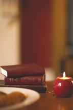 stack of Bibles, candle, and plate of food 