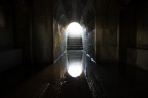 reflection in water at the bottom of a dark tunnel.